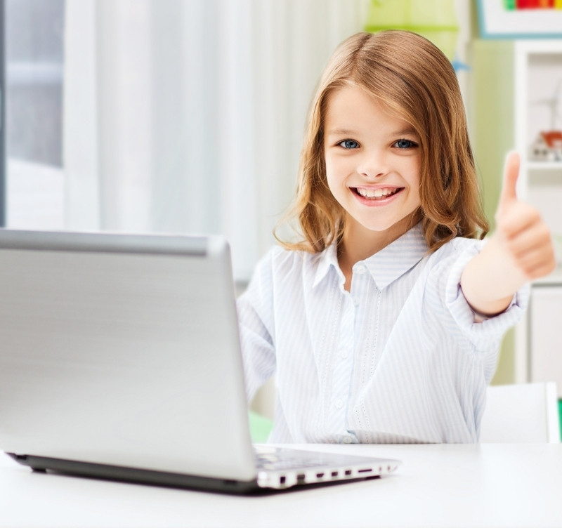 Happy girl giving a thumbs up for her maths and English online tuition while sitting at a computer